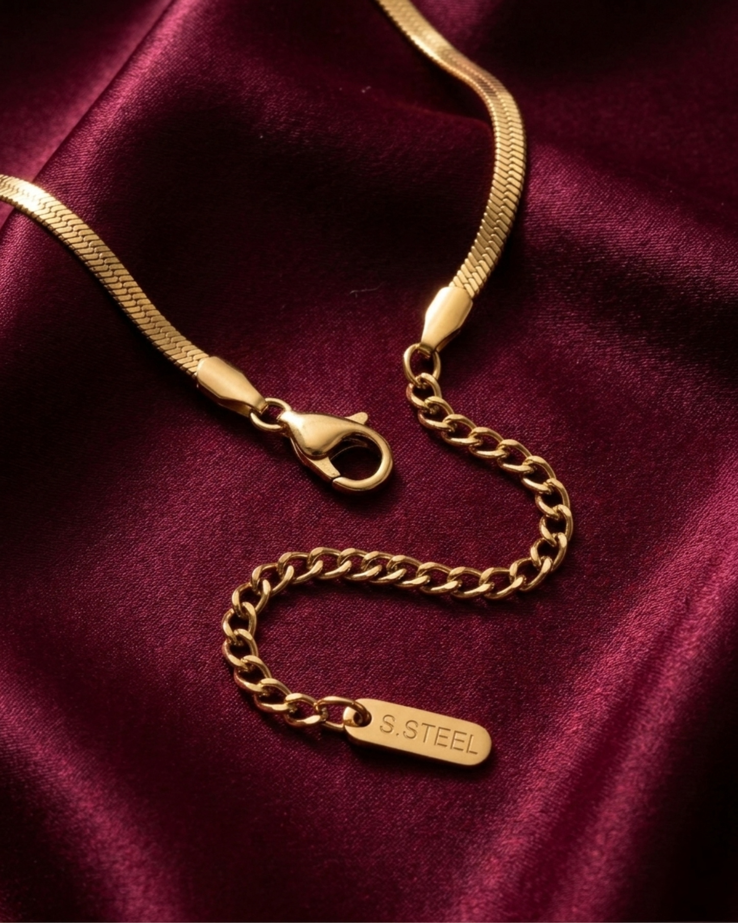 Gold chain necklace with clasp on a burgundy fabric background