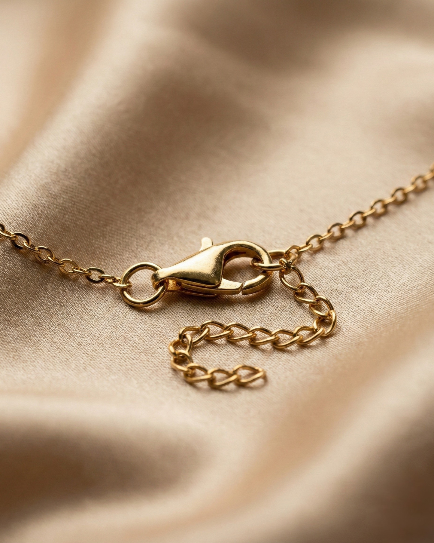 Gold chain necklace on a beige fabric background