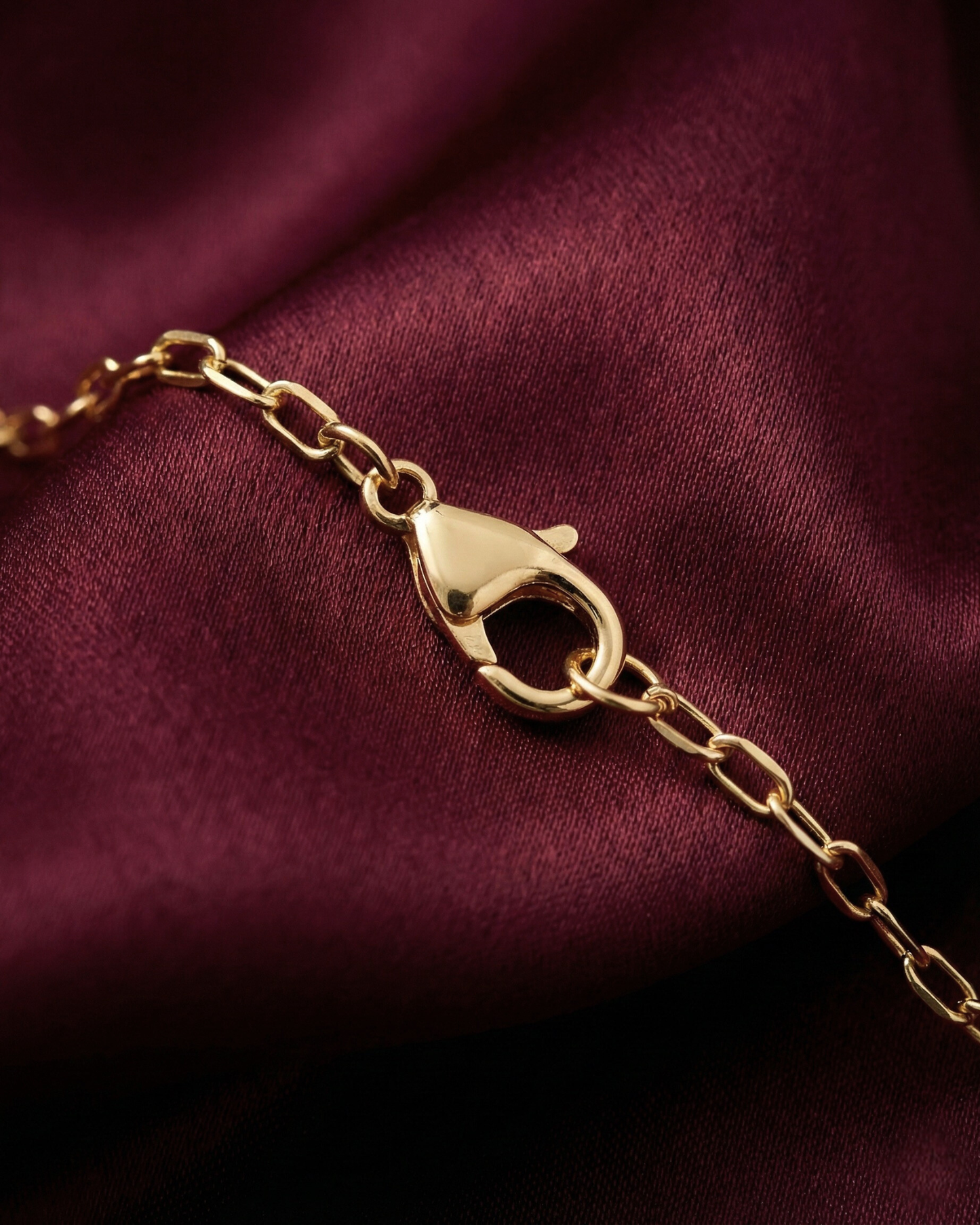 Gold bracelet with clasp on a burgundy fabric background