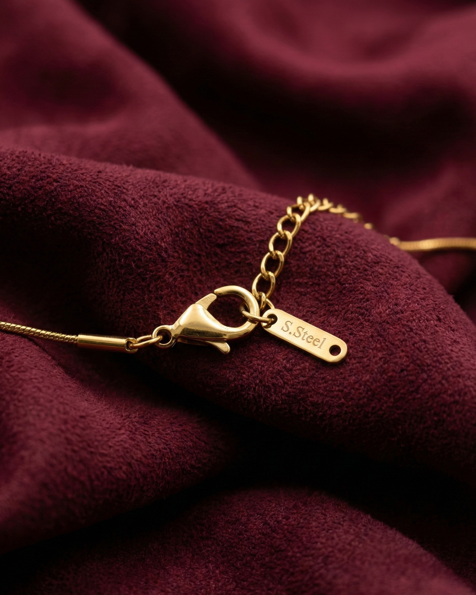 Gold bracelet with clasp on a burgundy fabric background
