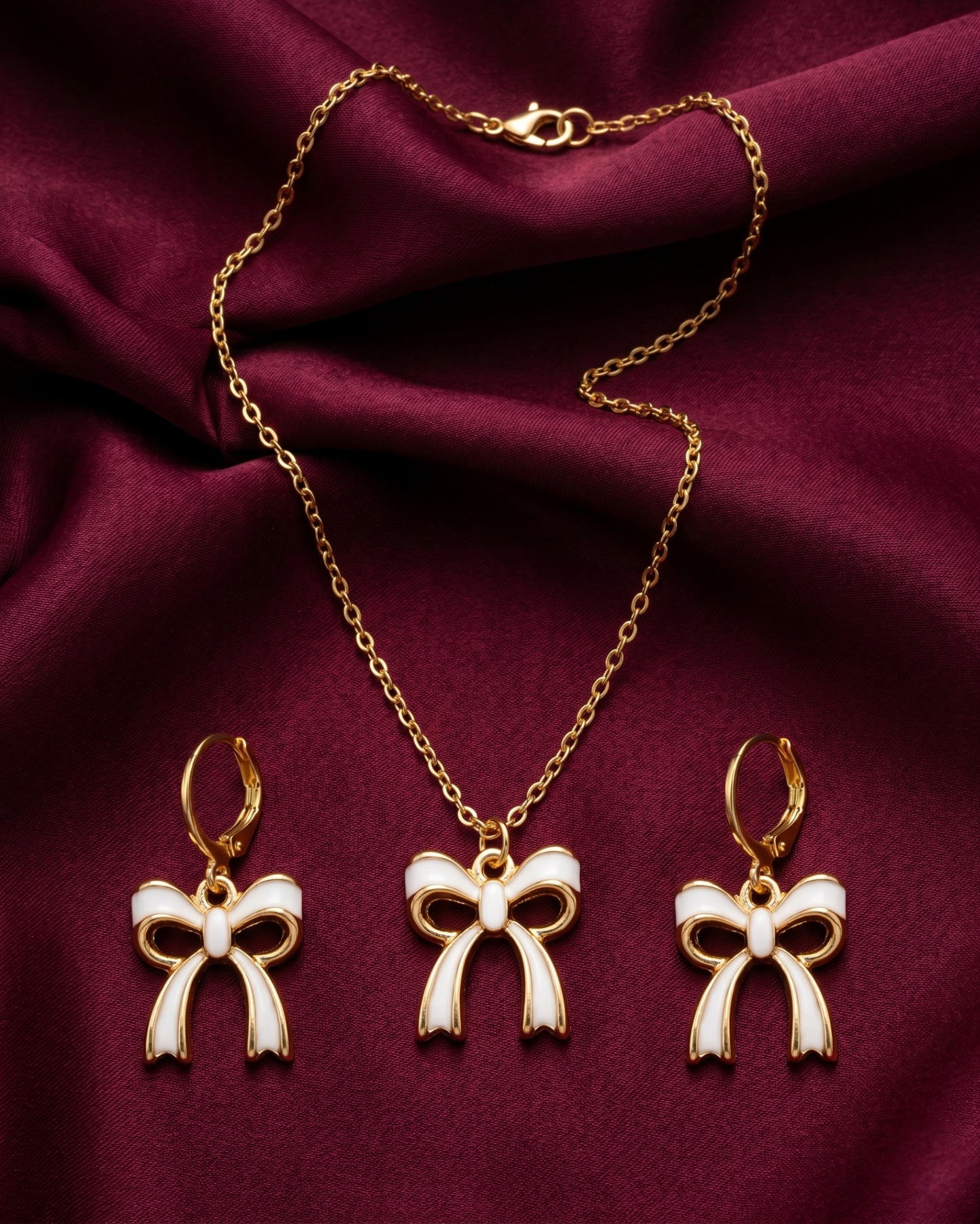 Gold plated white bow necklace and earrings set for women. 3 piece matching ribbon charm jewelry combo India. Lightweight office wear necklace and earring sets for working women. White enamel bow pendant and drop earrings alloy. Diwali, Navratri, and Rakhi jewelry gifts for wives. Gold tone festive neck and ear accessories for girls, women, and friends