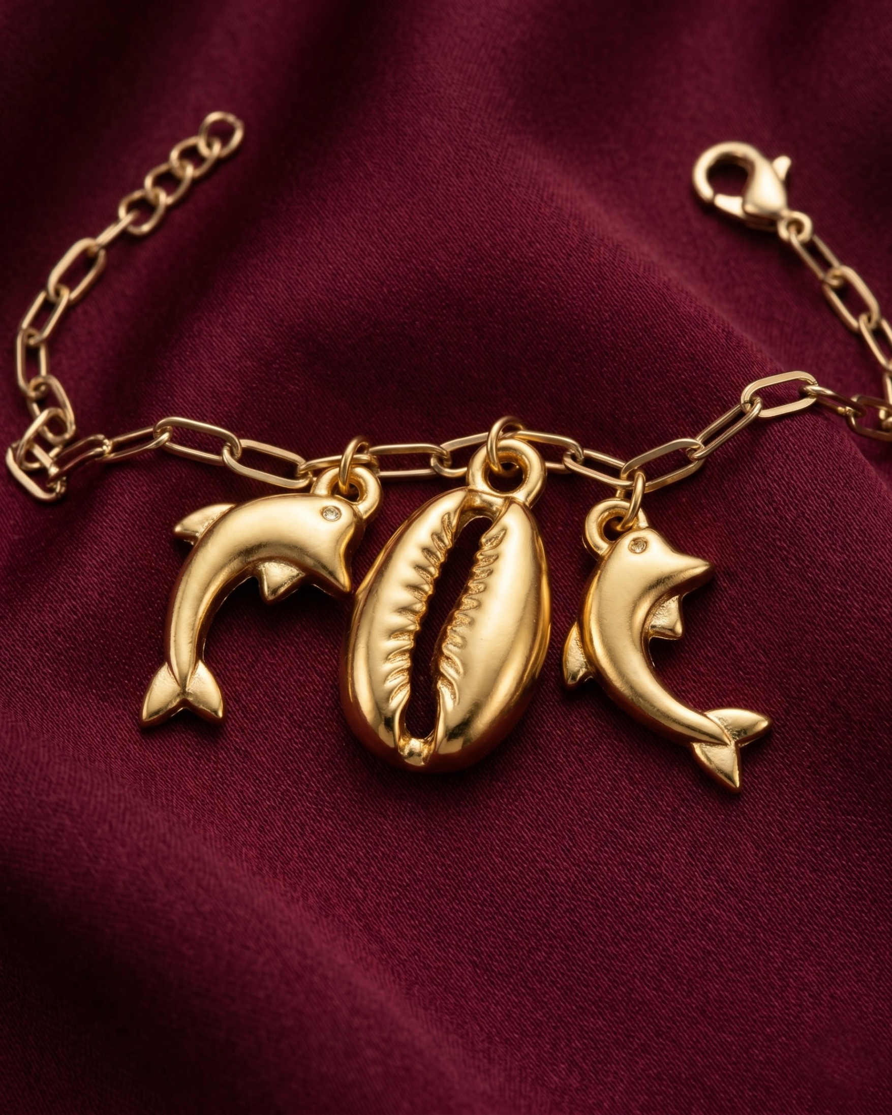 Gold plated cowrie shell and dolphin charm bracelet for women. Paperclip chain link marine charm bracelets India. Lightweight office wear jewelry for working women. Textured cowrie shell and dolphin charm bracelet set alloy. Holiday resort wear jewelry and gifts for wives. Gold tone beach theme wrist accessories for girls and friends