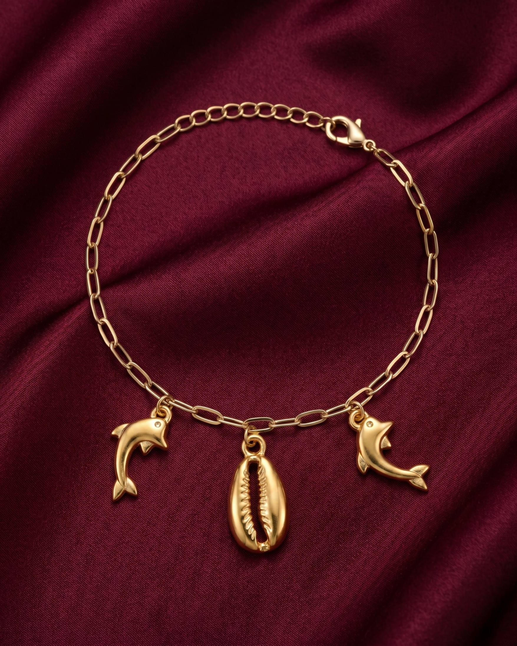 Gold plated cowrie shell and dolphin charm bracelet for women. Paperclip chain link marine charm bracelets India. Lightweight office wear jewelry for working women. Textured cowrie shell and dolphin charm bracelet set alloy. Holiday resort wear jewelry and gifts for wives. Gold tone beach theme wrist accessories for girls and friends
