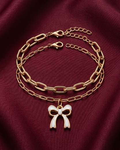 Gold plated white bow charm bracelet stack for women. 2 piece layered paperclip link bracelets India. Lightweight office wear jewelry for working women. White enamel ribbon charm bracelet set alloy. Diwali and Rakhi jewelry gifts for wives. Gold tone festive wrist accessories for girls, women, and friends.