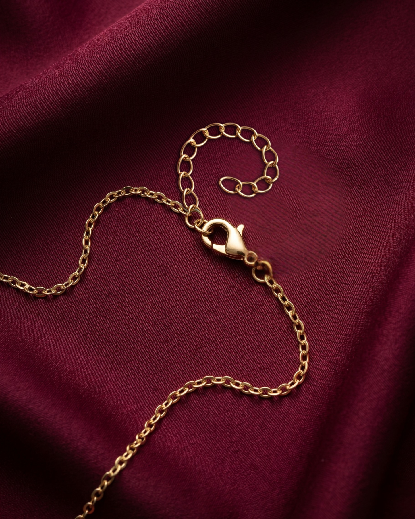 Gold chain bracelet on a burgundy fabric background
