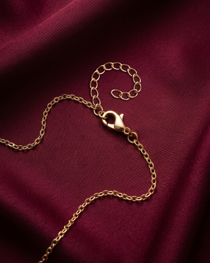 Gold chain bracelet on a burgundy fabric background