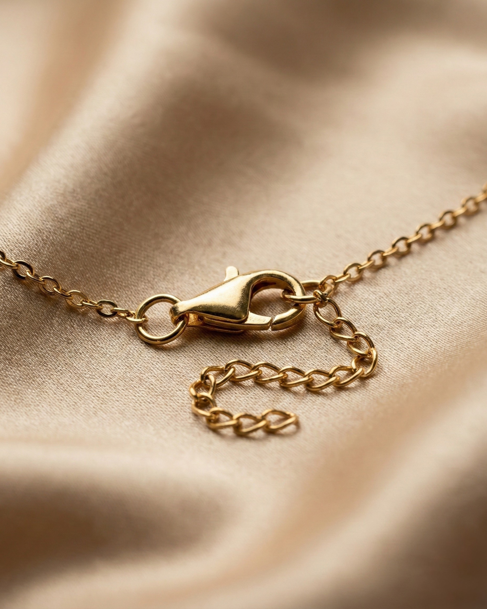 Gold chain necklace on a beige fabric background