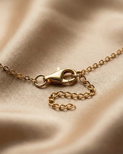 Gold chain necklace on a beige fabric background
