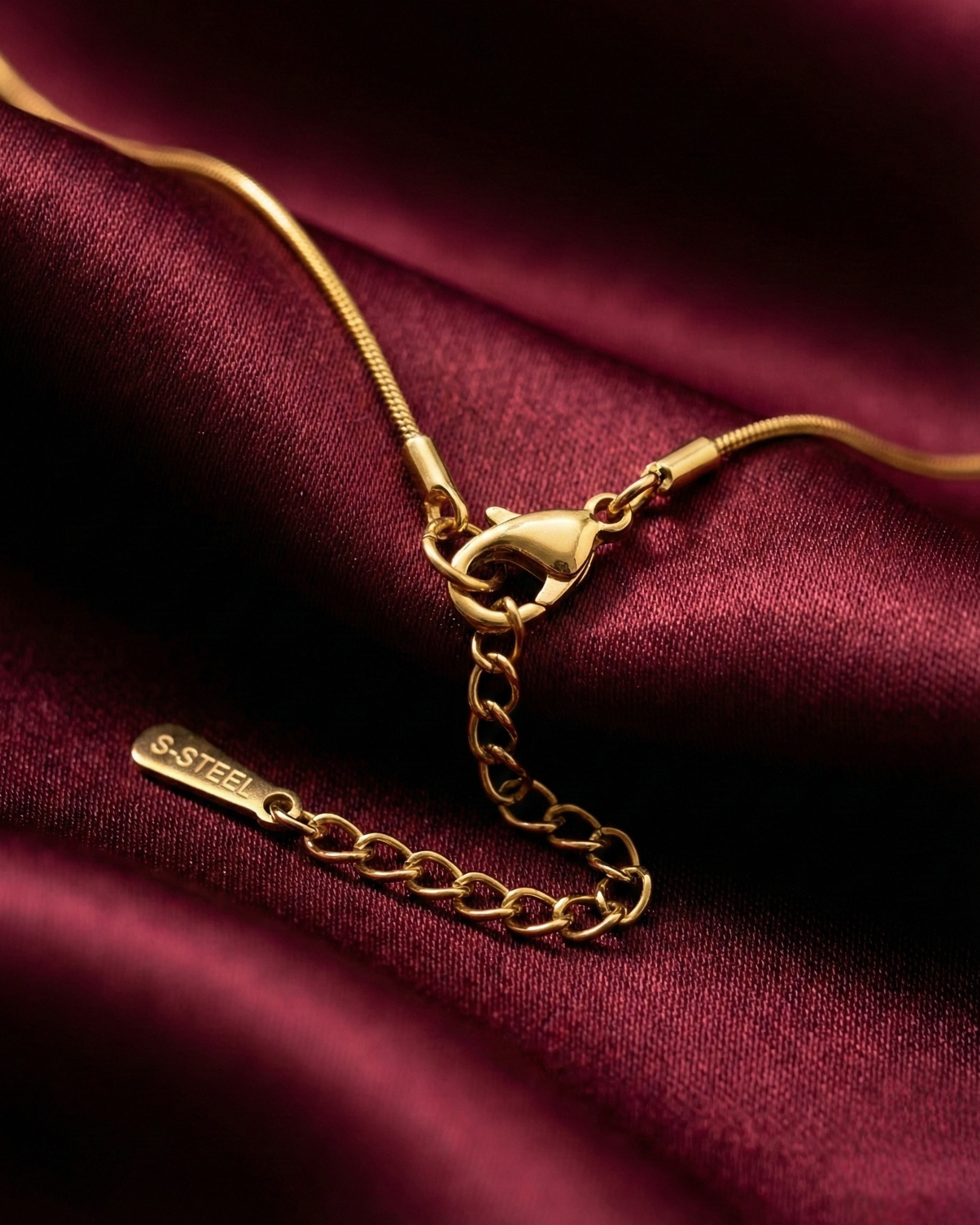 Gold necklace on a burgundy fabric background