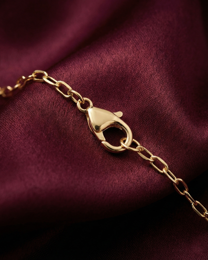 Gold bracelet with clasp on a burgundy fabric background