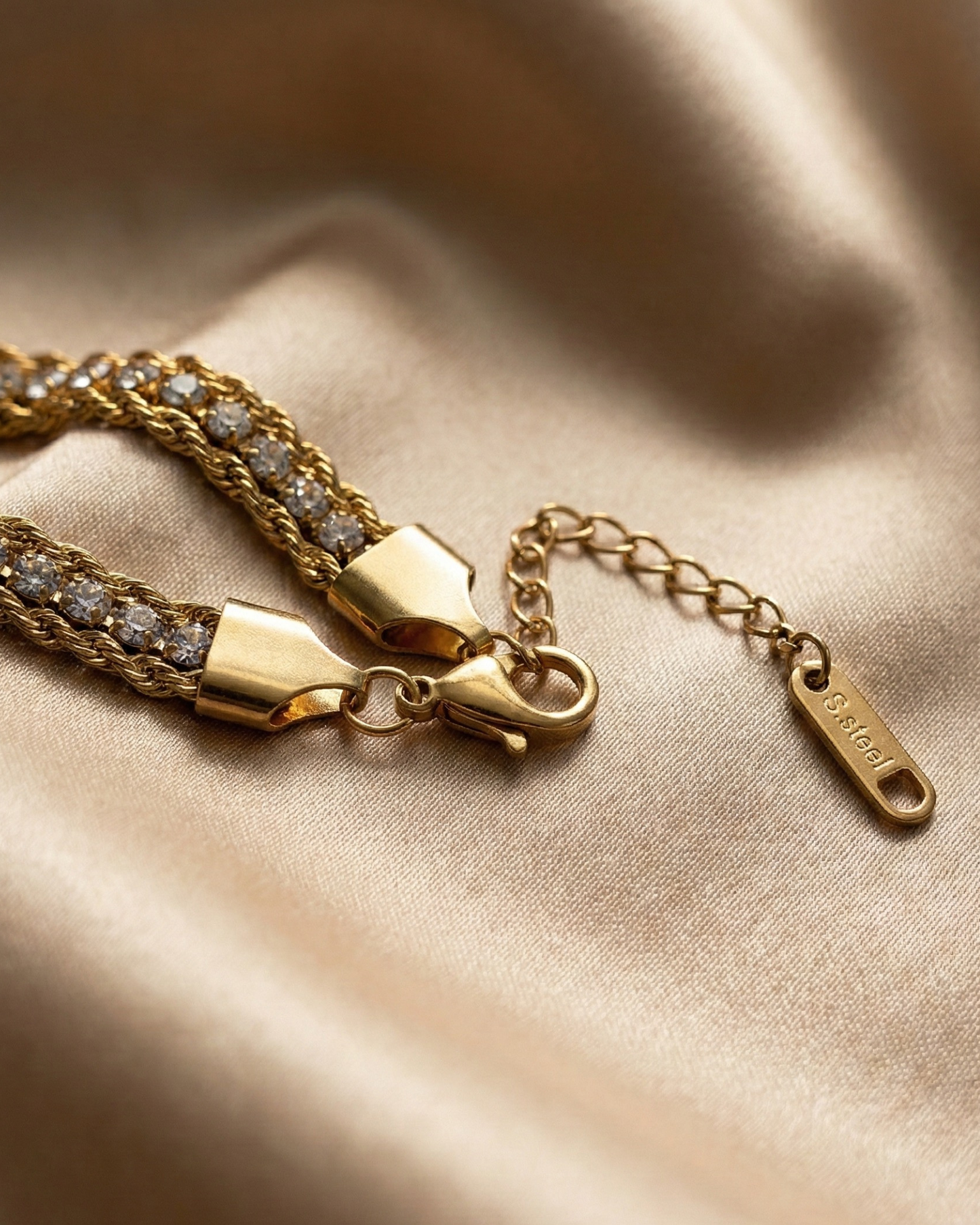 Gold bracelet with diamond accents on a beige fabric background