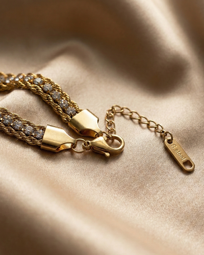Gold bracelet with diamond accents on a beige fabric background
