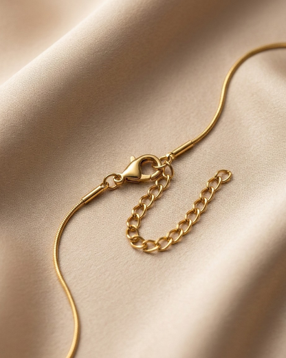 Gold chain necklace on a beige fabric background