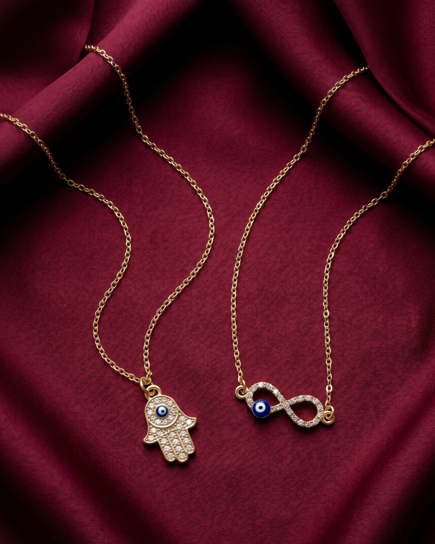 Gold plated evil eye and hamsa necklace set for women. 2 piece layered protective pendant jewelry India. Lightweight office wear necklaces for working women. Crystal studded hamsa hand and infinity charm necklace alloy. Diwali, Navratri, and Rakhi jewelry gifts for wives. Gold tone festive neck accessories for girls, women, and friends.